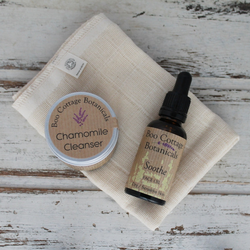 Aluminium lidded jar with brown label and amber bottle with brown label and black dropper pipette on cream face cloth all on whitewashed wooden background